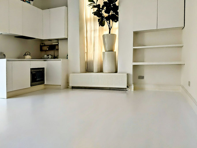 A modern kitchen featuring tradition pine floorboards sanded, gap filling and painted white that hide wood knots and marks creating a clean seamless look