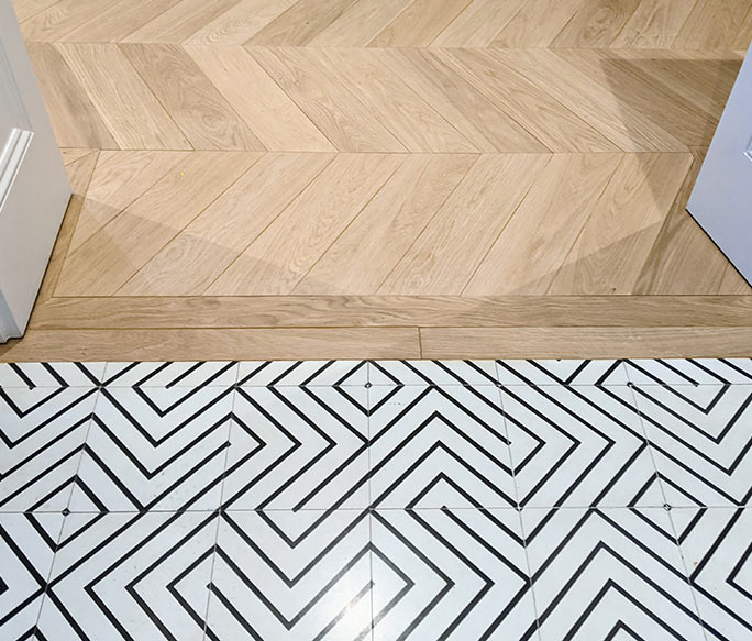 Flush transition between chevron oak parquet and geometric tiles #CraftedForLife