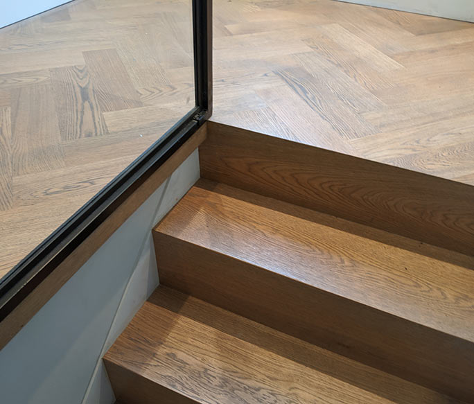 Oak herringbone landing transition to cladded stair treads #CraftedForLife