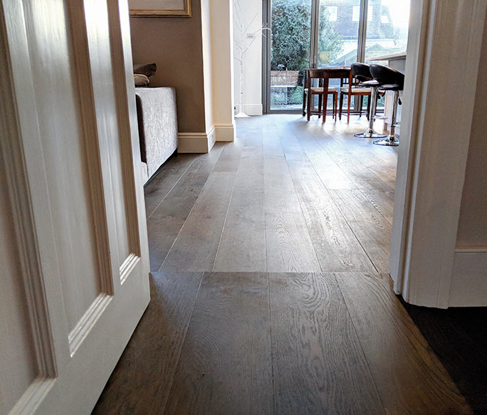 Oak plank floor transition across a step with continuous alignment #CraftedForLife