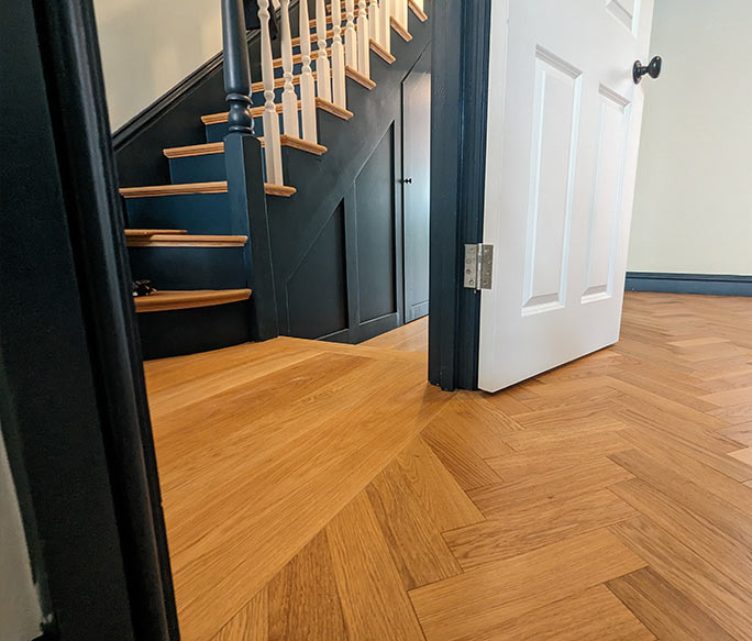 Transition from oak chevron parquet to straight planks at a doorway #CraftedForLife