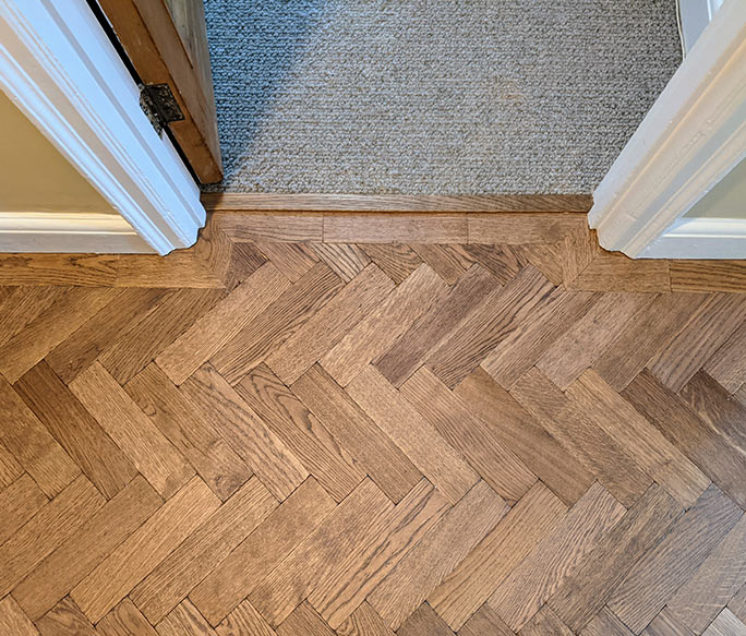 Transition from oak herringbone parquet to carpet at a doorway #CraftedForLife