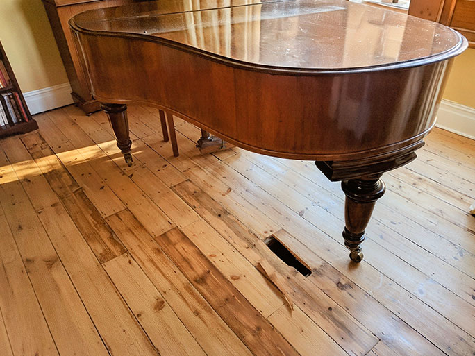 Under the heavy weight of the grand piano the old pine floorboards that were thinned and weakened due to repeated sanding broke and splintered