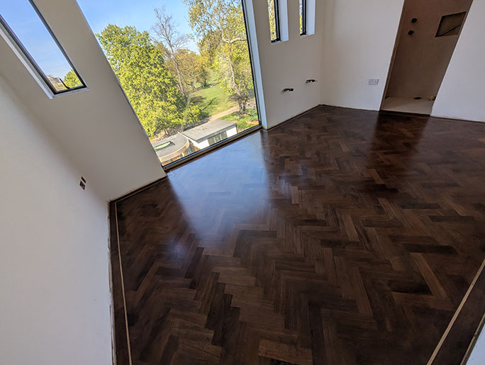 Walnut herringbone parquet with a single row border and contrasting oak tramline #CraftedForLife